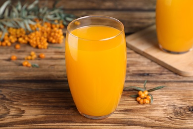 Photo of Sea buckthorn juice on wooden table, closeup