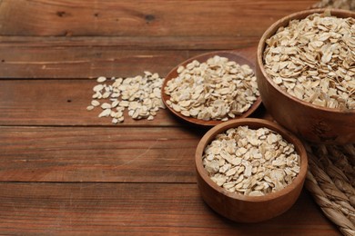 Photo of Bowls with oatmeal on wooden table. Space for text
