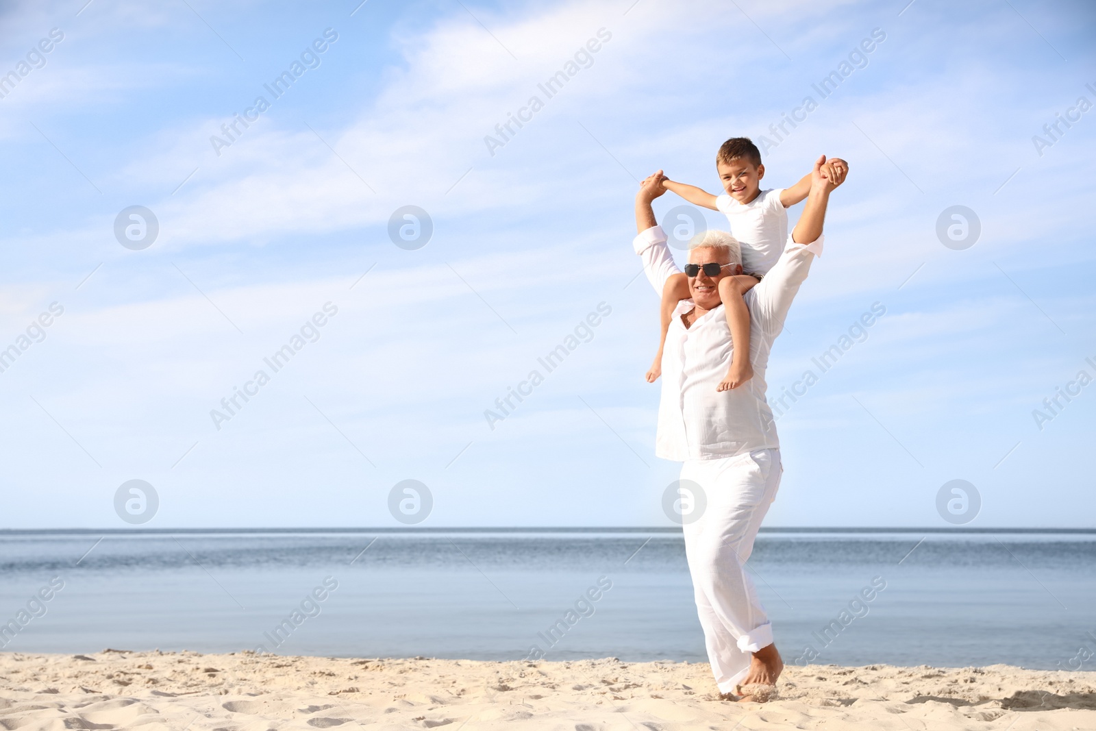 Photo of Cute little boy with grandfather spending time together on sea beach