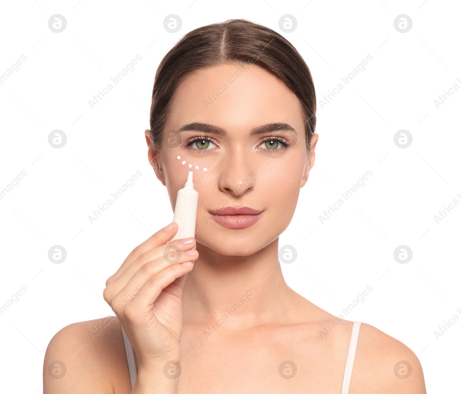 Photo of Young woman applying cream under eye on white background