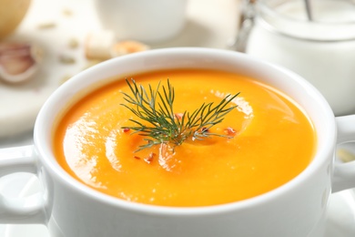 Photo of Delicious pumpkin soup in bowl on table, closeup