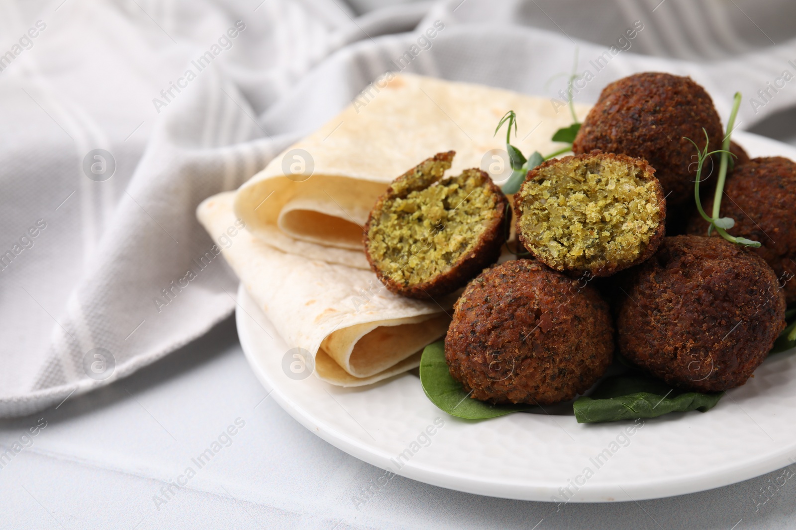 Photo of Delicious falafel balls, herbs and lavash on white table