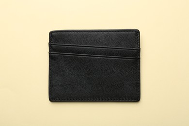 Empty leather card holder on beige background, top view