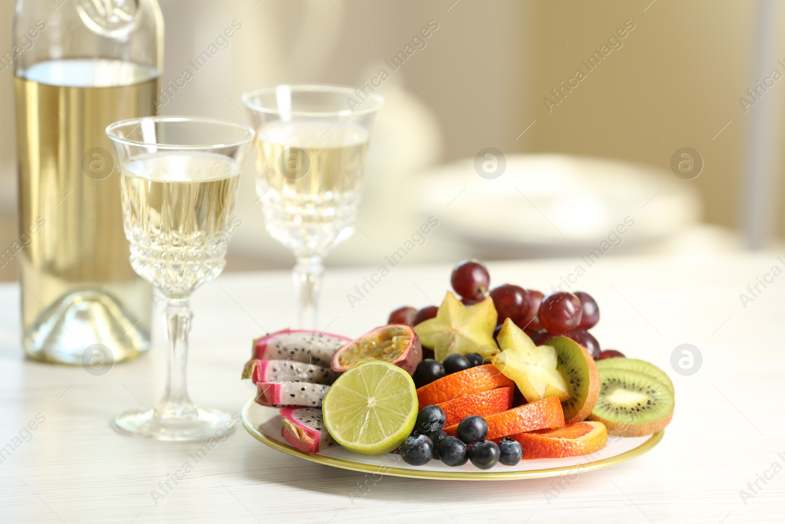 Photo of Delicious exotic fruits and wine on white table