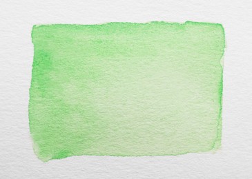 Photo of Green watercolor rectangle on white canvas, top view