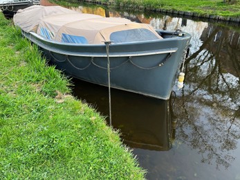 Photo of View of canal with moored boat near green shore