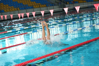 Photo of Young athletic man jumping into swimming pool