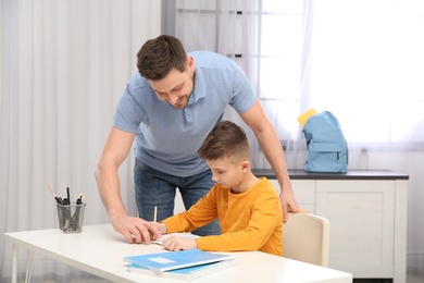 Photo of Dad helping his son with homework in room