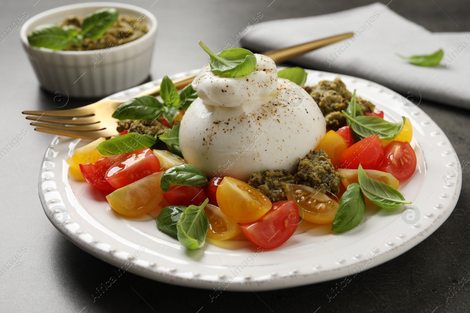 Photo of Delicious burrata salad served on grey table, closeup