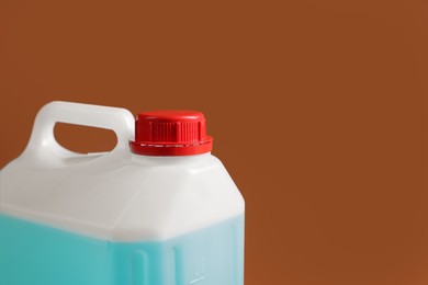 Photo of Plastic canister with blue liquid on brown background, closeup. Space for text