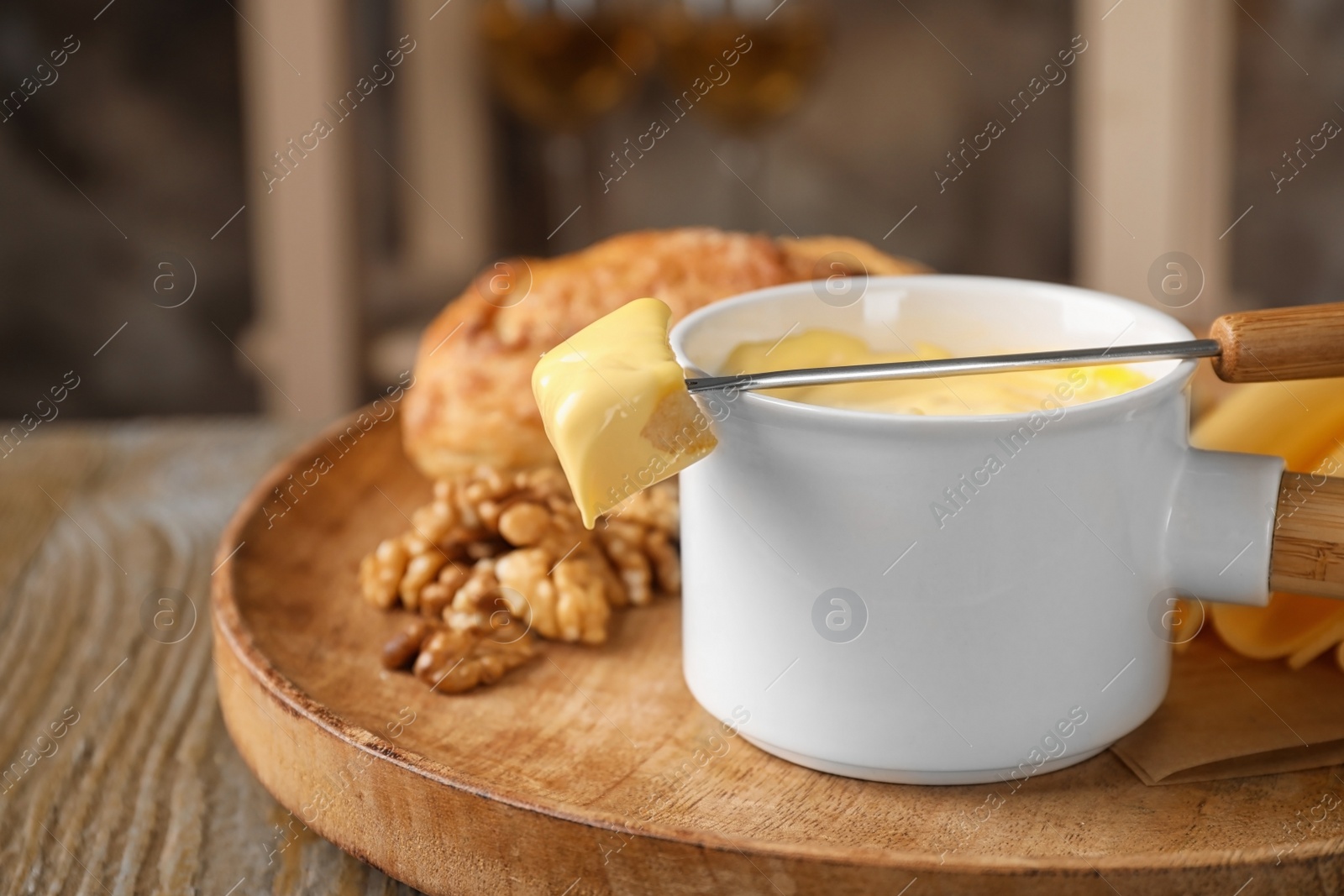 Photo of Pot of tasty cheese fondue and products on wooden table