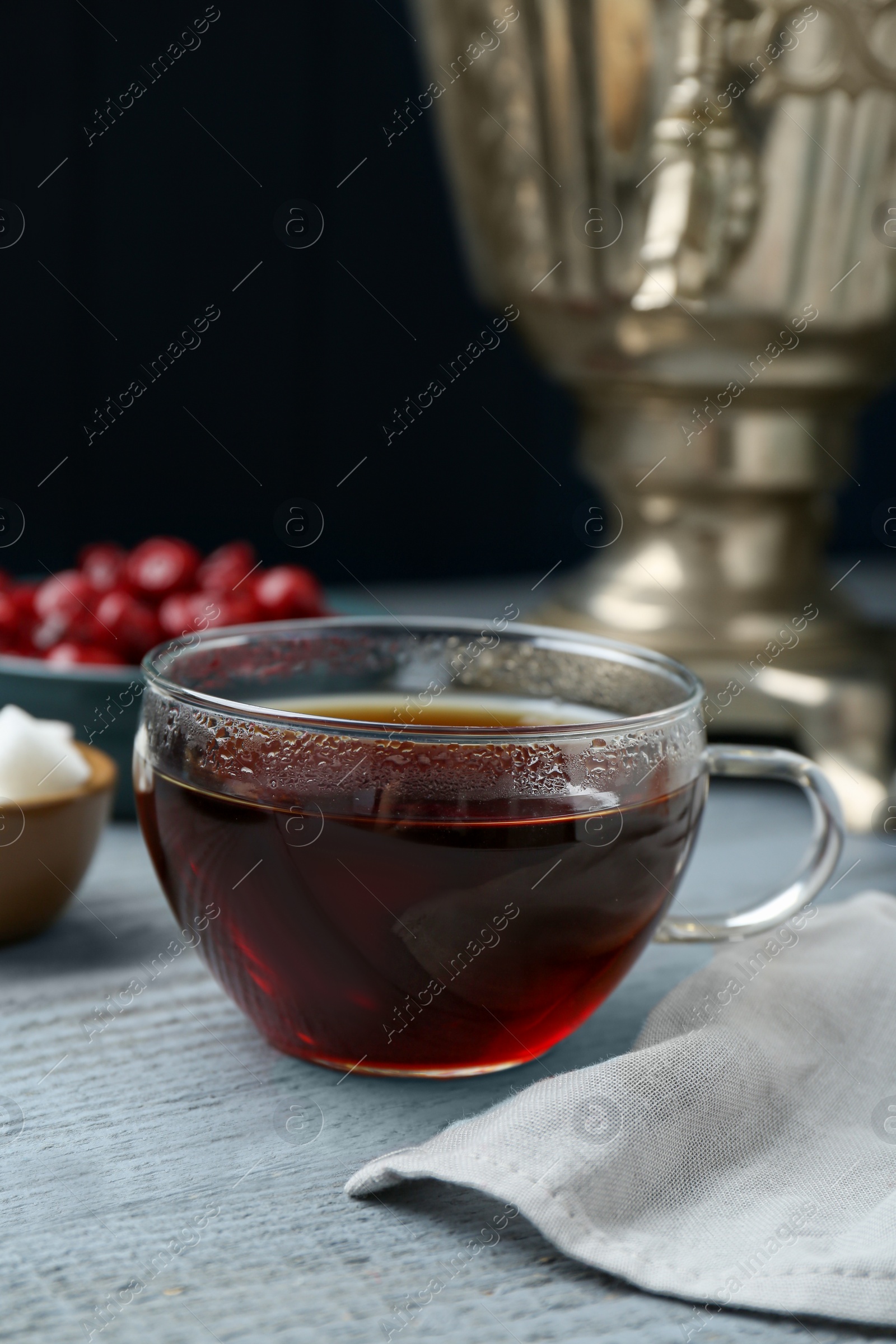 Photo of Glass cup of aromatic tea on light blue wooden table