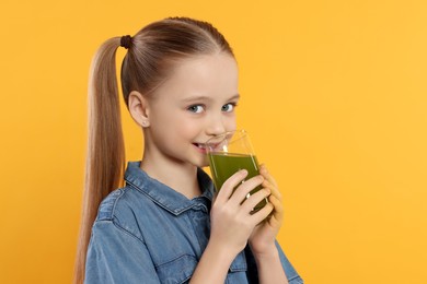 Cute little girl drinking fresh juice on orange background, space for text