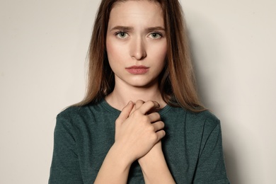Photo of Portrait of upset young woman on light background