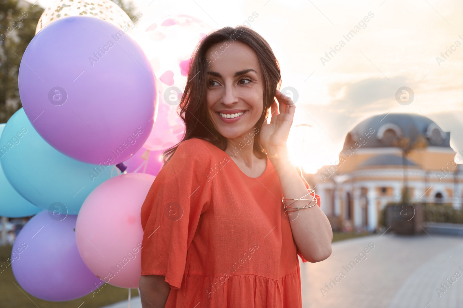 Photo of Cheerful young woman with color balloons outdoors on sunny day