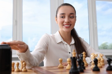 Woman turning on chess clock during tournament at table indoors