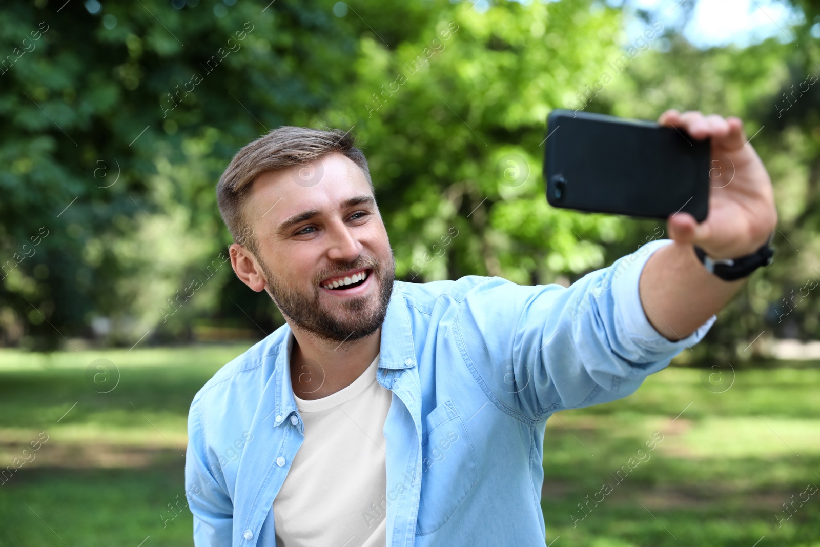 Photo of Happy young man taking selfie in park