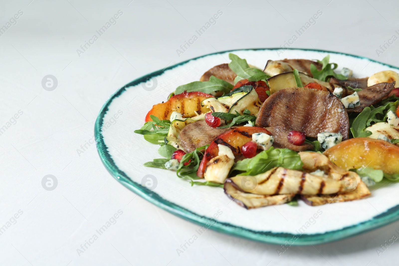 Photo of Delicious salad with beef tongue, grilled vegetables, peach and blue cheese on white table, closeup. Space for text