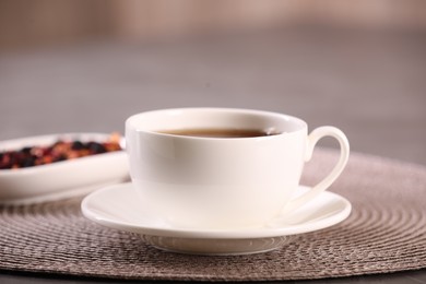 Photo of Aromatic tea in cup and saucer on table, closeup