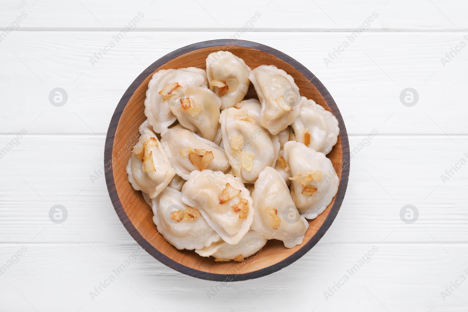 Photo of Delicious dumplings (varenyky) with potatoes and onion on white wooden table, top view