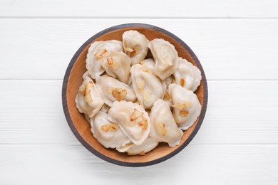 Delicious dumplings (varenyky) with potatoes and onion on white wooden table, top view