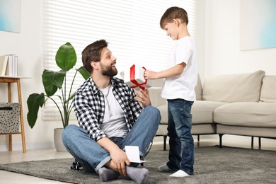 Photo of Happy Father's Day. Son giving gift box to his father with greeting card at home