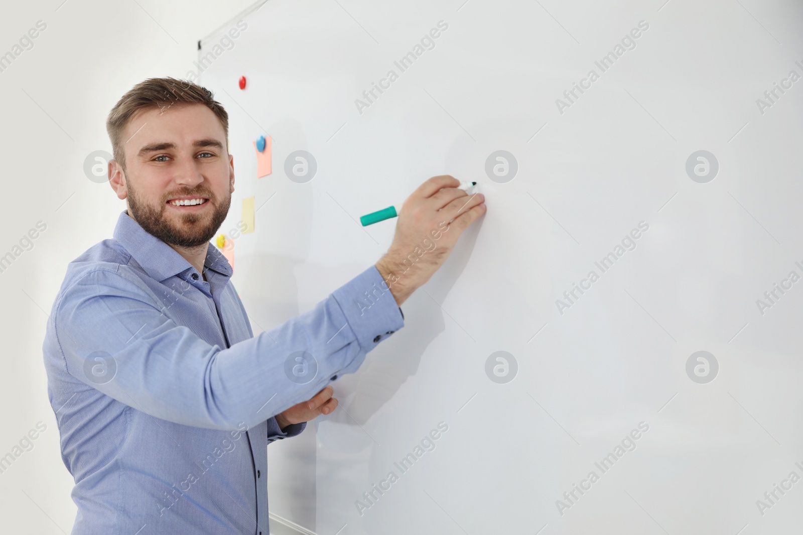 Photo of Portrait of young teacher writing on whiteboard in classroom