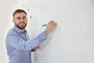 Portrait of young teacher writing on whiteboard in classroom