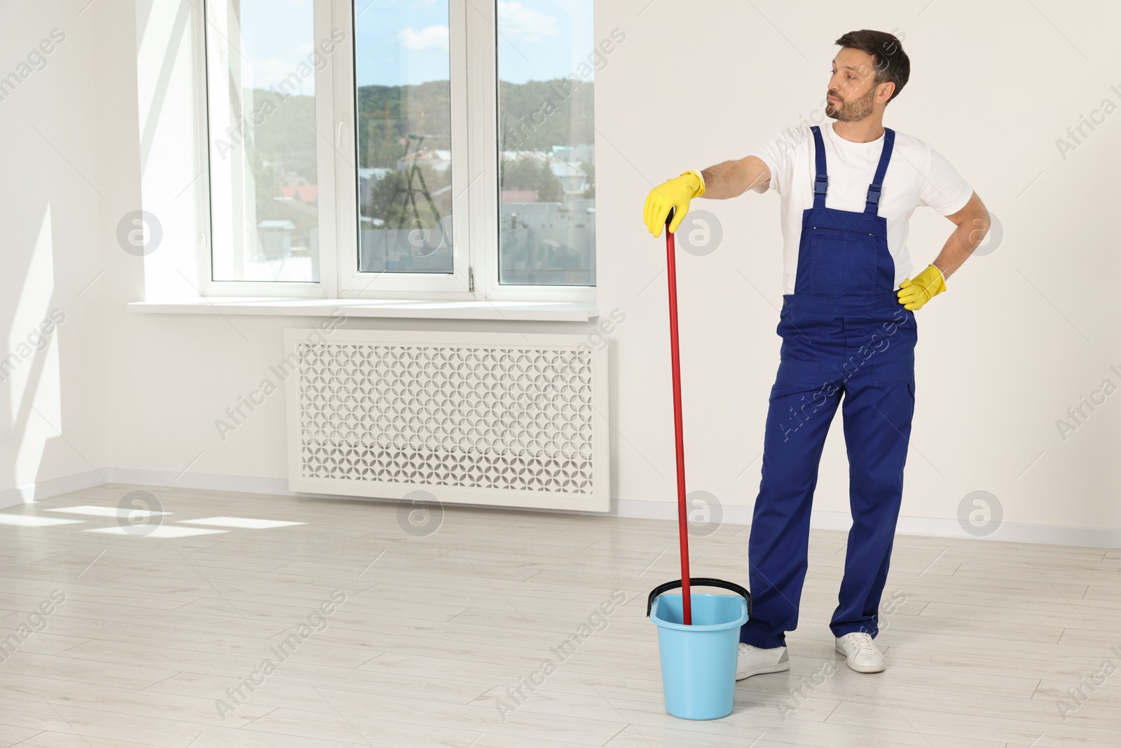 Photo of Man with mop in bucket indoors. Space for text