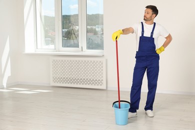 Man with mop in bucket indoors. Space for text