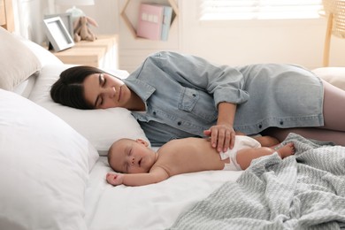 Photo of Mother with her cute baby sleeping on bed at home