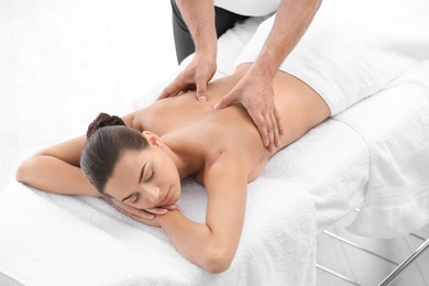 Photo of Relaxed woman receiving back massage in wellness center