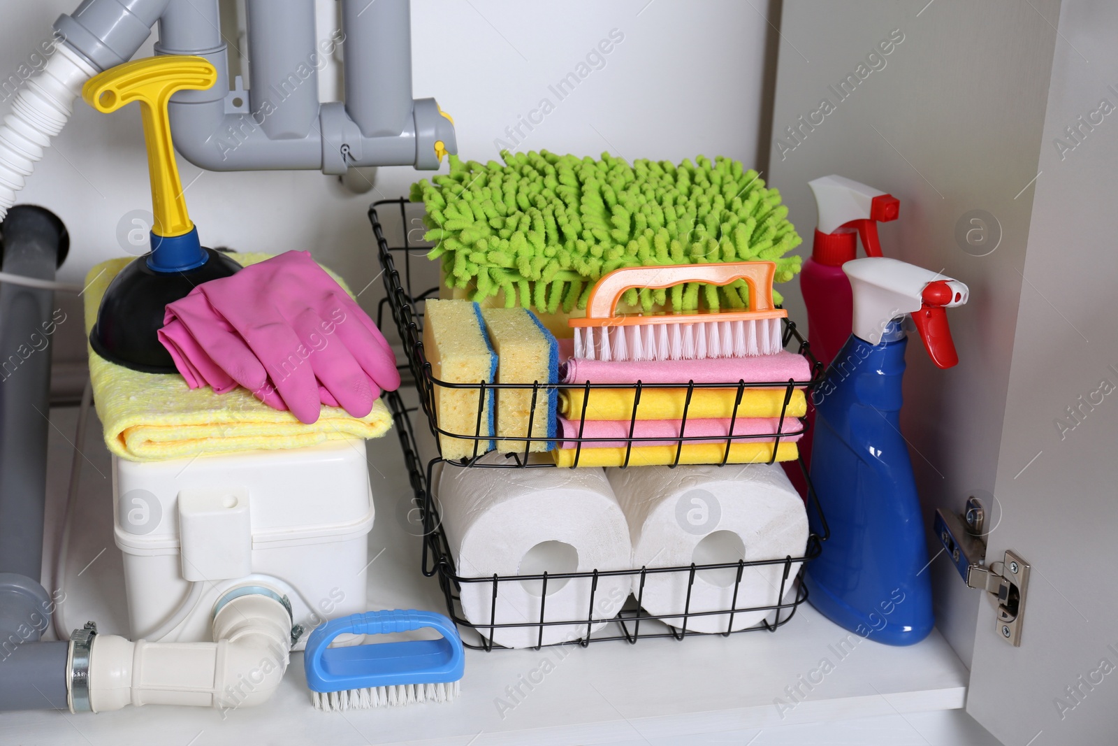 Photo of Open under sink cabinet with different cleaning supplies in kitchen