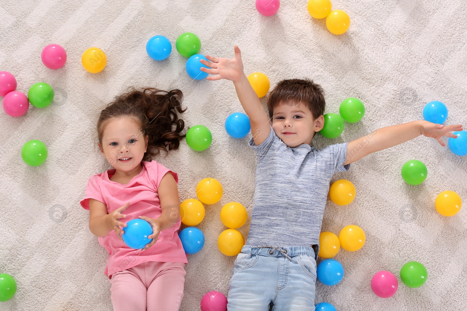 Photo of Cute little children with toys on floor indoors, top view