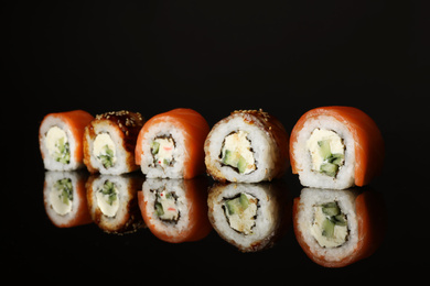 Photo of Delicious sushi rolls on black mirror surface