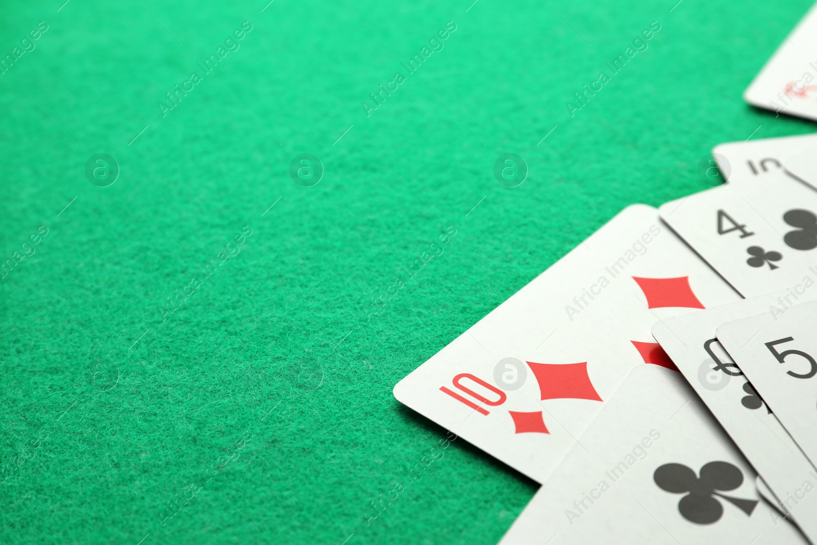 Photo of Scattered playing cards on green table, closeup. Space for text