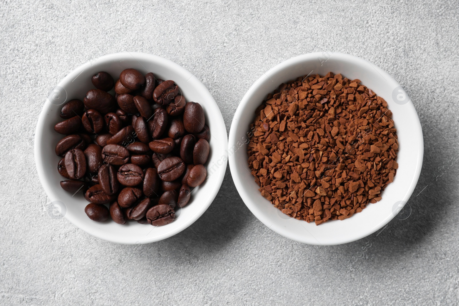 Photo of Bowls with roasted beans and instant coffee on light grey table, flat lay