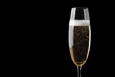 Photo of Glass of fizzy champagne on black background, closeup. Space for text