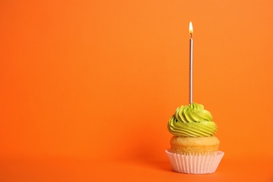 Birthday cupcake with candle on orange background, space for text
