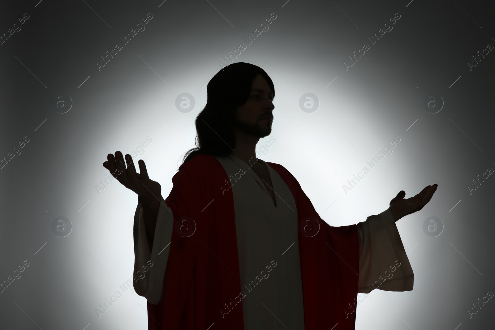 Photo of Silhouette of Jesus Christ with outstretched arms on color background