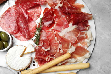 Photo of Tasty prosciutto served on light grey marble table, flat lay