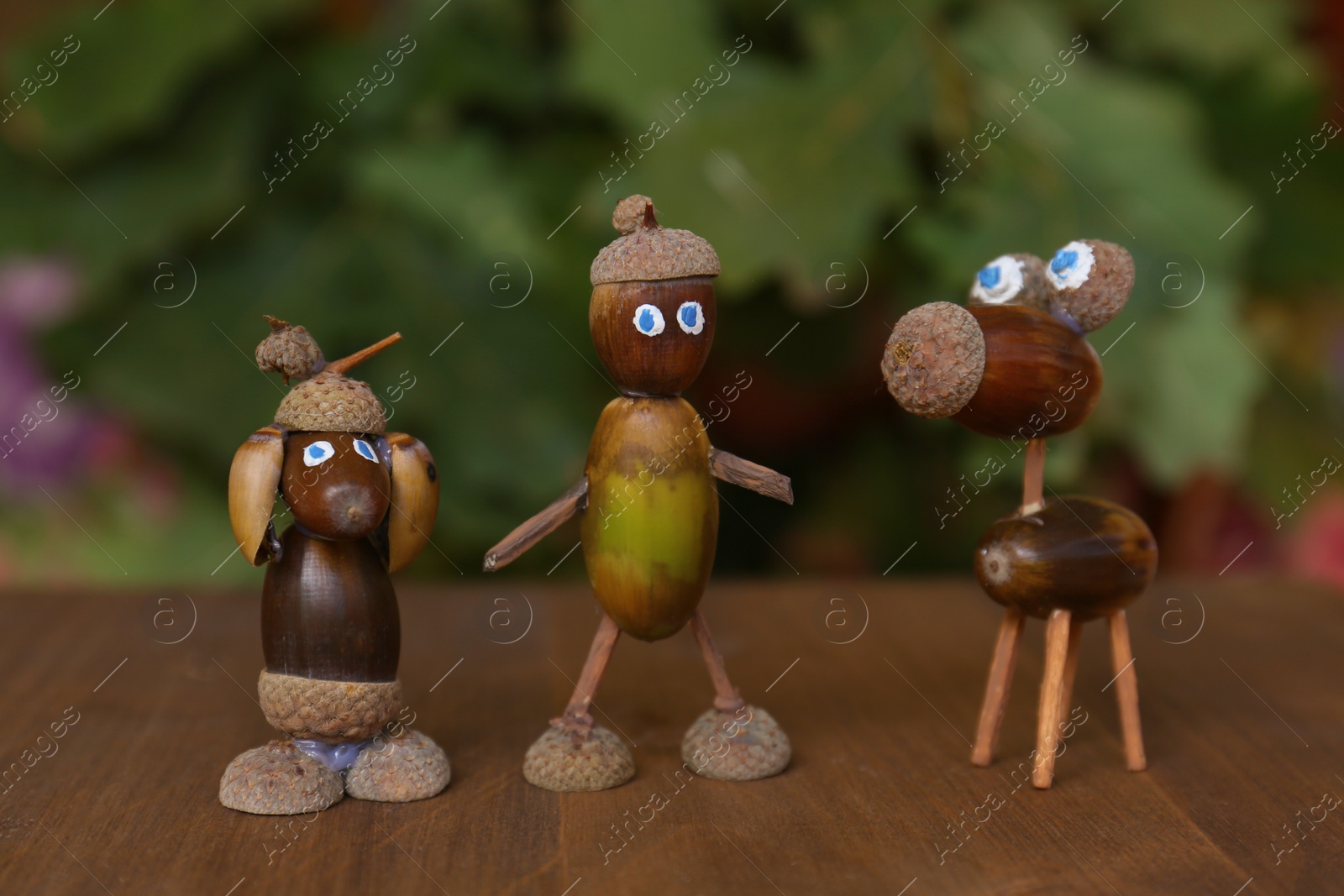 Photo of Cute figures made of acorns on wooden table