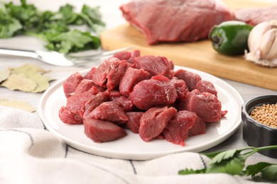 Photo of Plate with pieces of raw beef meat on table