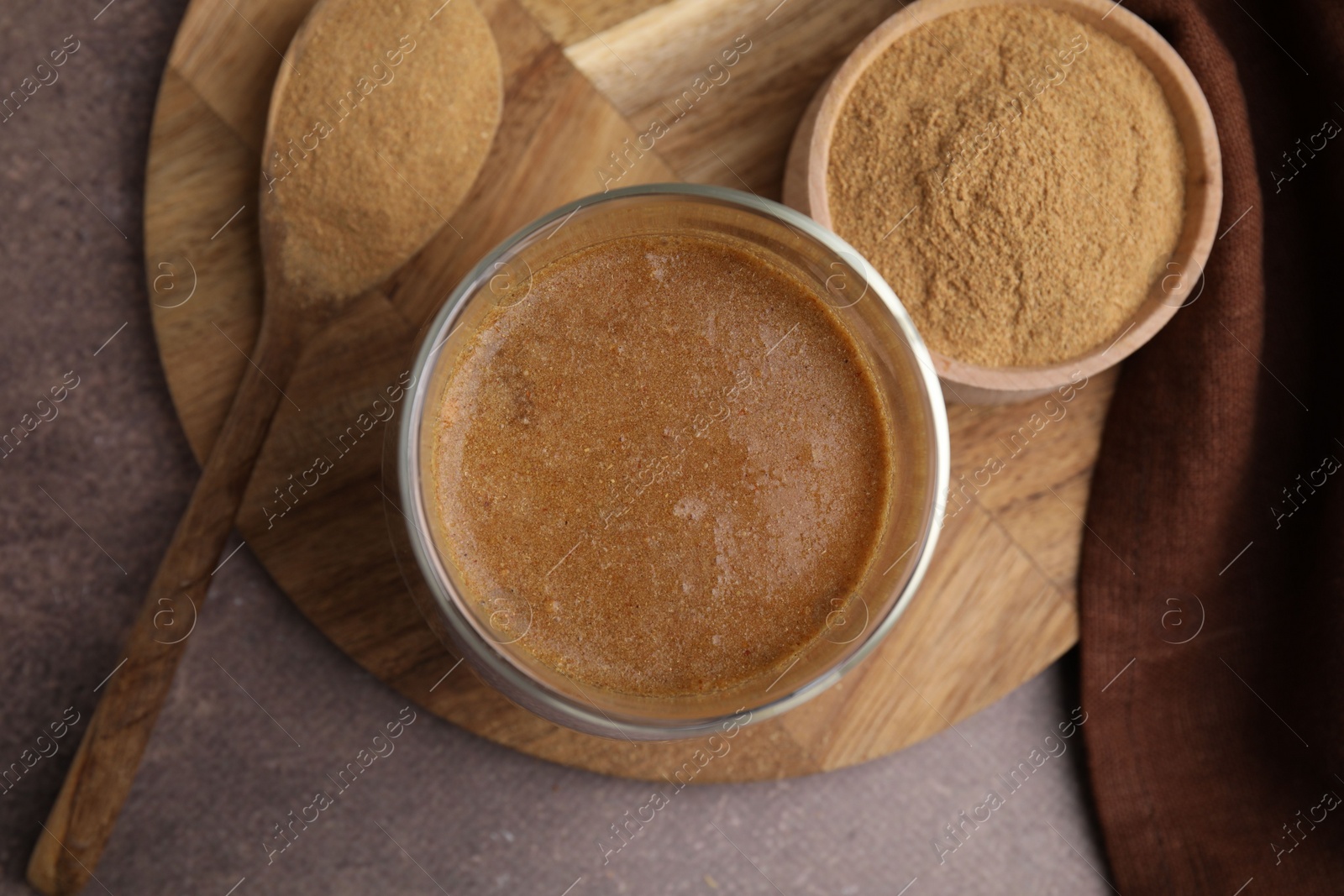 Photo of Soluble fiber with water in glass, powder and spoon on brown table, top view