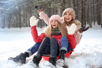Photo of Mother and daughter having fun in forest on snow day