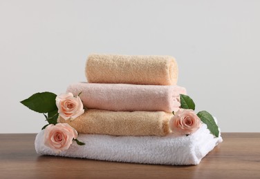 Photo of Stack of folded colorful towels with roses on wooden table