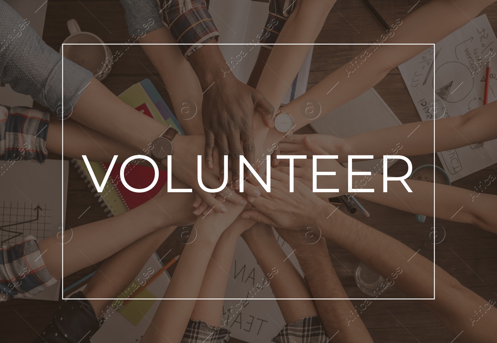 Image of Group of volunteers putting hands together at table, top view