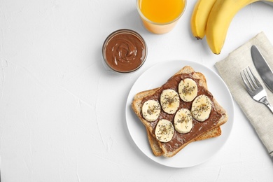 Photo of Slice of bread with chocolate paste and banana on white table, flat lay. Space for text