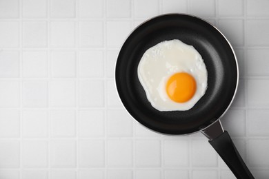 Tasty fried egg in pan on white table, top view. Space for text