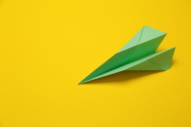 Photo of Handmade light green paper plane on yellow background, above view. Space for text